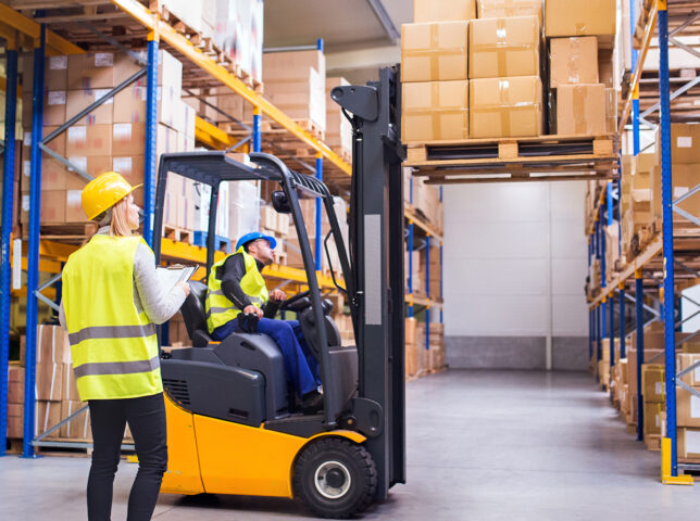 Workers in a warehouse moving goods with a forklift
