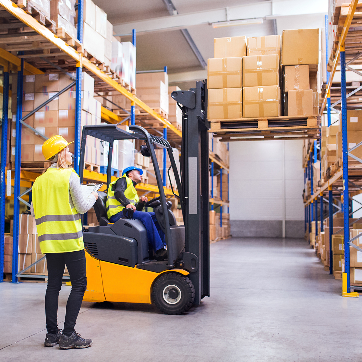 Workers in a warehouse moving goods with a forklift
