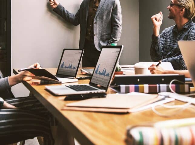 People in an office workshop with laptops showing data graphs