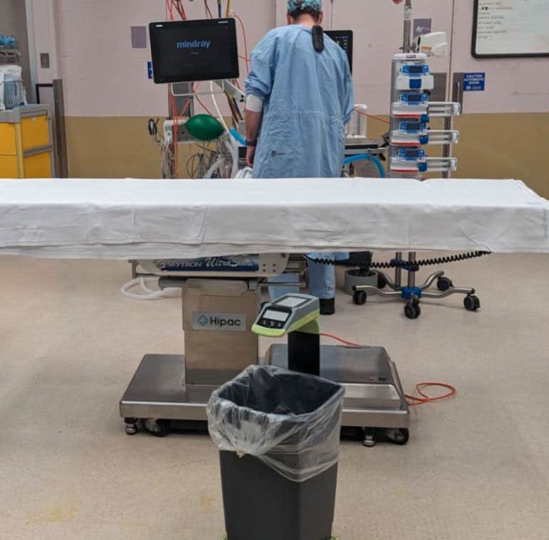 Person in surgical scrubs in operating theatre with SureWaste system.