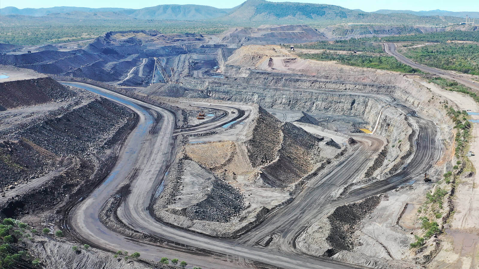 Open cut mine site with haul road and deep pit walls that can create communication blind spots